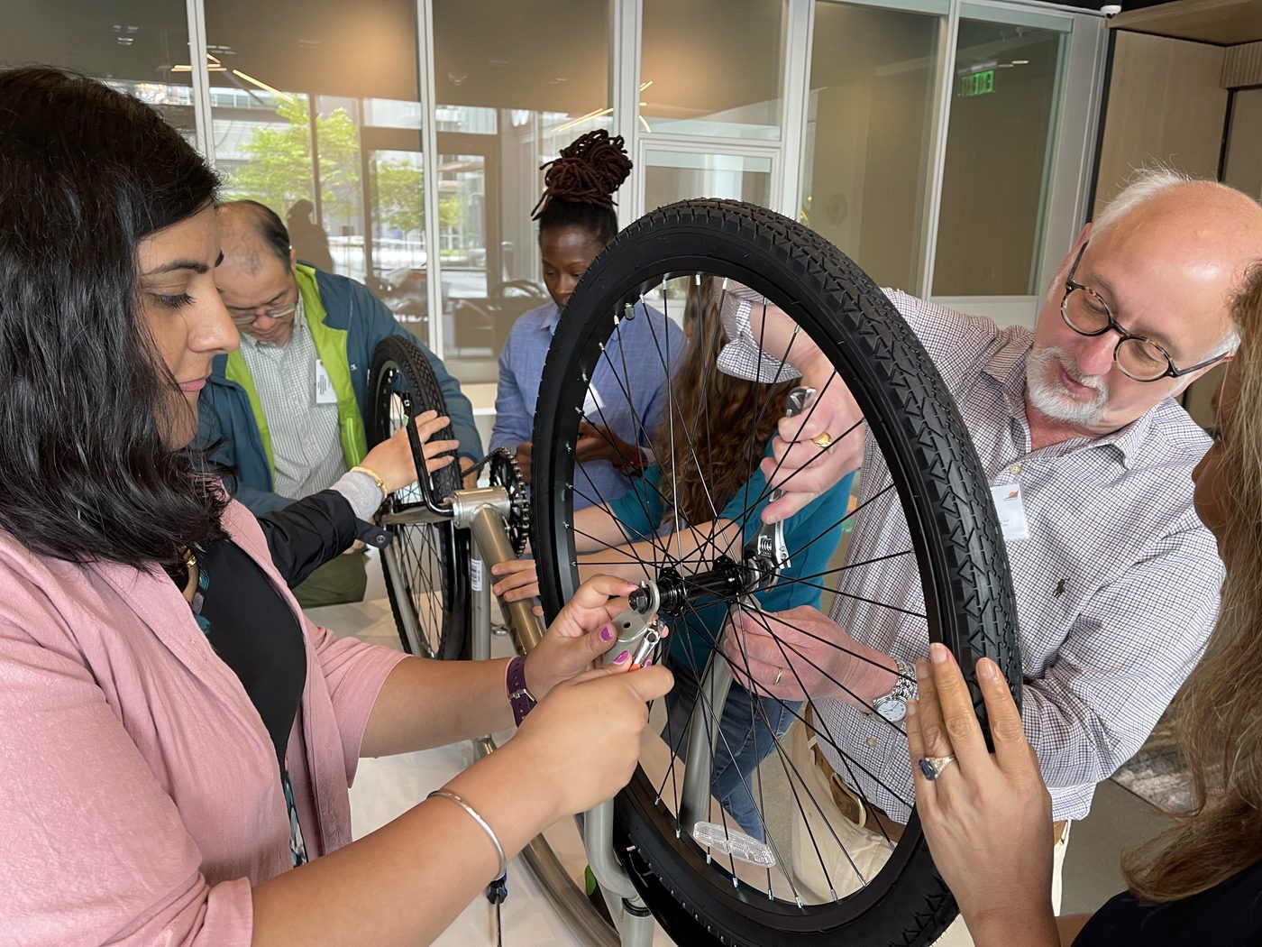 Teammates work together on a bicycle wheel.