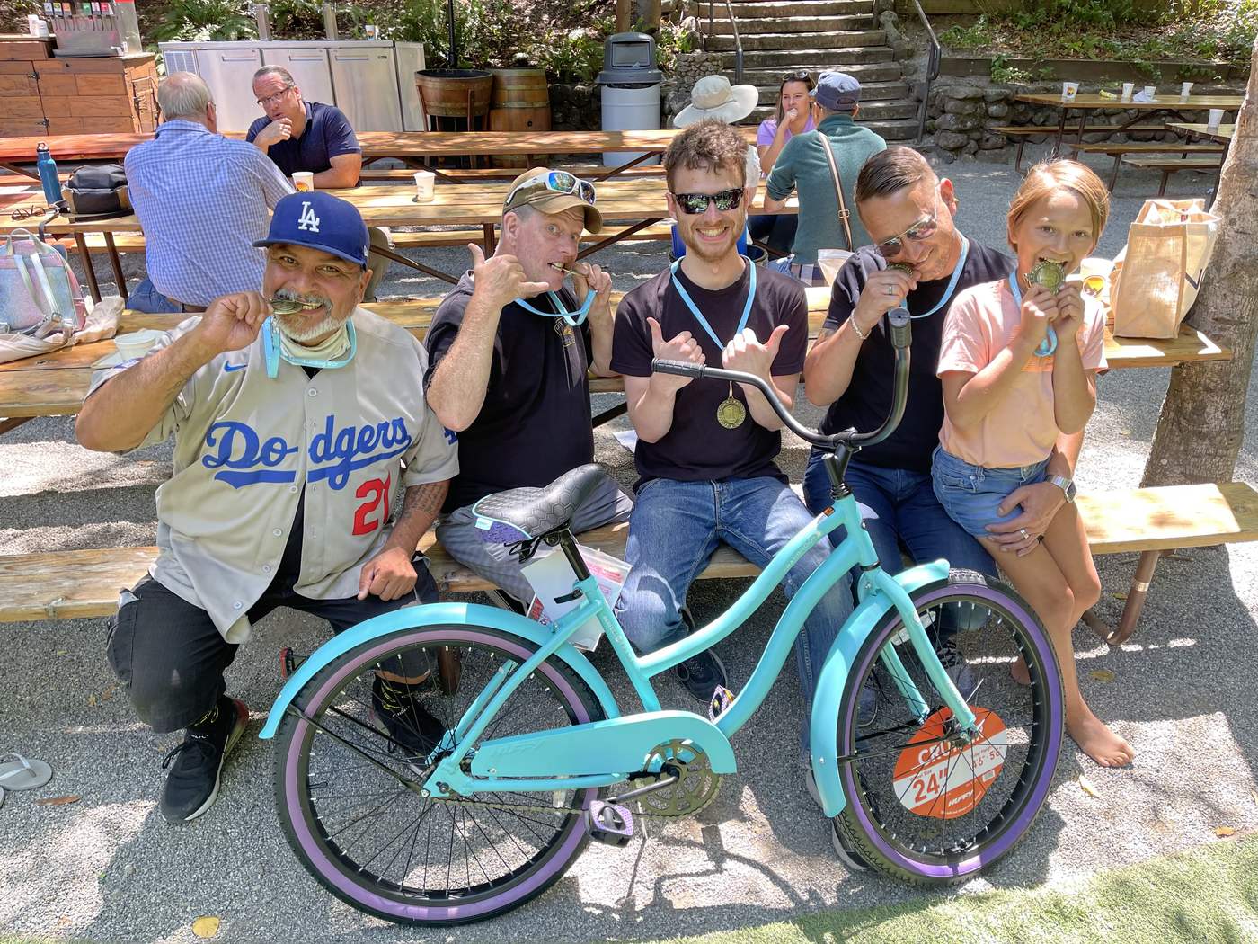 Medal-winning teammates celebrate beside their finished bicycle.